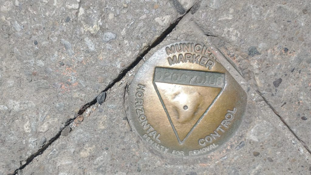 Bronze disc survey monument in concrete with words Municipal Marker Horizontal Control