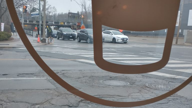 intersection with cars and a bike seen through a window